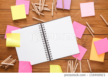 Don't forget things. Top view of stationery supplies - open notepad, colorful blank memory stickers and memo notes, variety of pencils on wooden office table with copy space, flat lay, template 138408921