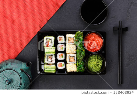 Colorful sushi and rolls platter in japanese restaurant, with teapot and chopsticks top view. Colorful sushi and rolls platter in japanese restaurant, with teapot and chopsticks top view. 138408924