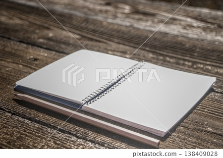 An open, pristine white ring notebook and pencil on a wooden table, low saturation. An open, pristine white ring notebook and pencil on a wooden table, low saturation. 138409028