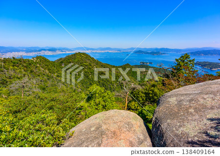 [Miyajima, Mt. Misen] The giant, strangely shaped rocks at the summit and the beautiful archipelago of the Seto Inland Sea spread out below. 138409164