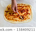 Top view of woman hands spreading organic tomato sauce on handmade pizza dough with spoon, traditional italian recipe preparation in cozy home kitchen, domestic culinary hobby lifestyle photography 138409211