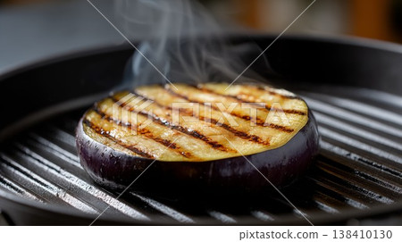 Grilled eggplant slice on ridged pan with steam rising close view cooking process 138410130