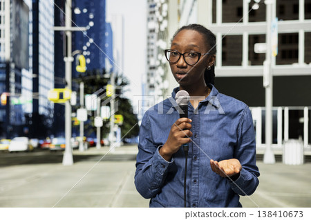 Presenting information, mic, and field reporter on city street speaking towards camera. Reporting live news update, microphone and African american journalist on metropolitan downtown area avenue Presenting information, mic, and field reporter on city street speaking towards camera. Reporting live news update, microphone and African american journalist on metropolitan downtown area avenue 138410673