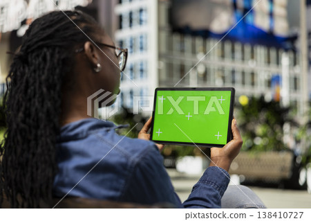 Green screen mockup tablet, sitting on city park bench and person watching movies. Relaxing, chroma key device and African american young girl enjoying TV shows entertainment outside Green screen mockup tablet, sitting on city park bench and person watching movies. Relaxing, chroma key device and African american young girl enjoying TV shows entertainment outside 138410727
