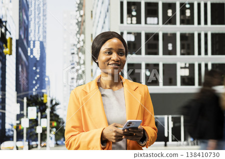Portrait of african american professional woman waiting at red light in intersection, walking the busy business district with a big urban crowd. Pedestrians group with different routines. Portrait of african american professional woman waiting at red light in intersection, walking the busy business district with a big urban crowd. Pedestrians group with different routines. 138410730