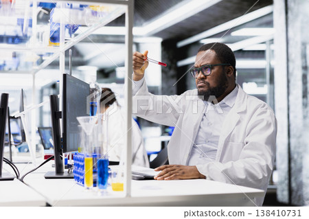 Clinical microbiologist in lab looking at blood sample in test tube. Medical research facility professional analyzing sanguine fluid specimen in vial used for medical research 138410731
