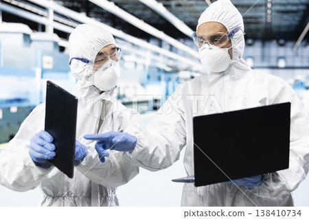 Engineering team in microchip industrial plant testing silicon wafer batches with software. Teamworking colleagues monitoring semiconductor manufacturing facility gear readouts with devices 138410734
