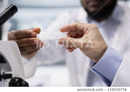 Close up shot of laboratory technicians team inspecting specimen slide for microscopy study. Teamworking lab scientists review cytology slide for clinical testing procedure 138410736