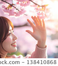 A heartwarming spring portrait: A woman reaches out and smiles at cherry blossoms in full bloom, illuminated by the setting sun. 138410868