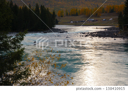 The surface of the Kanas River, shimmering in the sunset, and the autumn forest. The surface of the Kanas River, shimmering in the sunset, and the autumn forest. 138410915