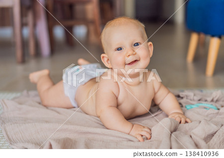 Baby lying on play mat learning to crawl and get on all fours. Infant practicing motor skills and development at home. Early childhood growth, milestones and active learning concept 138410936