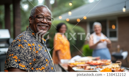 Smiling senior man in patterned shirt at outdoor cookout with food table; two women blurred in background with string lights 138412212