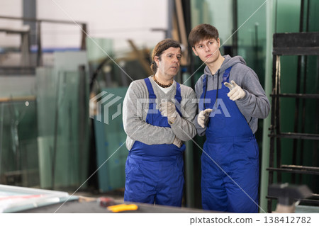 Adult and young man discussing work in glass factory Adult and young man discussing work in glass factory 138412782