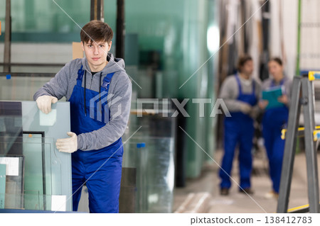 Guy glazer employee in blue overall works in glass processing shop Guy glazer employee in blue overall works in glass processing shop 138412783