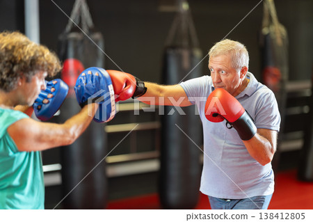 Older amateur boxer working pads with partner Older amateur boxer working pads with partner 138412805