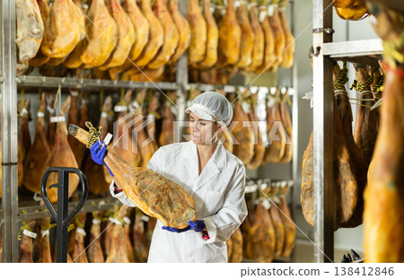 Female worker checks the quality of jamon at jamon factory 138412846