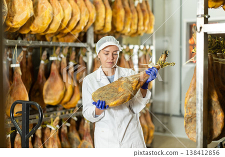 Girl places jamon on jamonero to cut it into pieces. Ham factory Girl places jamon on jamonero to cut it into pieces. Ham factory 138412856
