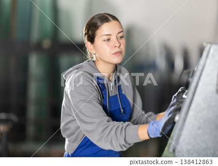 Girl workshop employee switches toggle switch on control panel 138412863