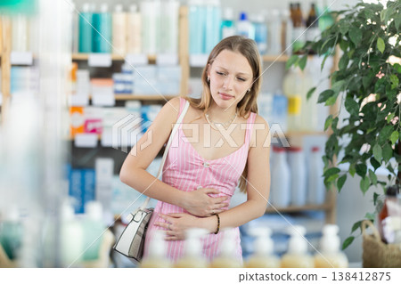 Woman experiences stomach pain while buying in supermarket Woman experiences stomach pain while buying in supermarket 138412875