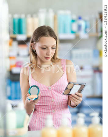 Woman in a dress choosing cosmetics in pharmacy Woman in a dress choosing cosmetics in pharmacy 138412912