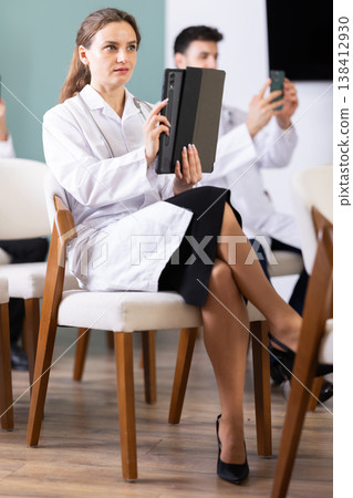 Medical students or doctors using mobile phones to scan QR-code during interactive lesson 138412930