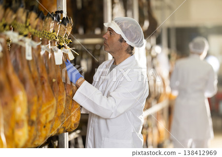 Man employee checks jamon. Quality control Man employee checks jamon. Quality control 138412969