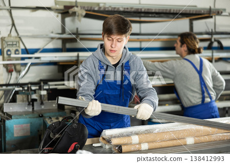Young guy taking steel profile in warehouse Young guy taking steel profile in warehouse 138412993