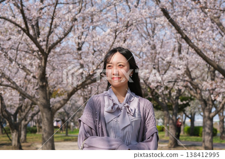 A young woman smiling under a cherry tree in full bloom A young woman smiling under a cherry tree in full bloom 138412995