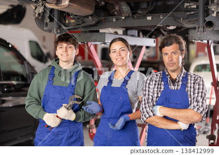 Portrait of team of auto mechanics near cars in car service center Portrait of team of auto mechanics near cars in car service center 138412999