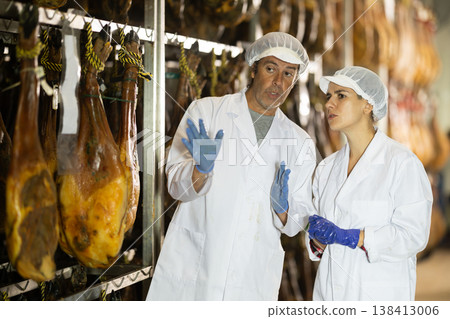Man and woman workers checking the quality of jamon 138413006