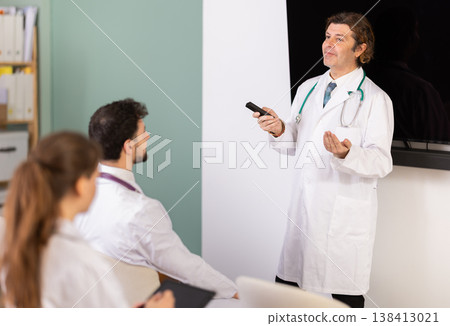Male doctor explaining medical topic to students using digital board Male doctor explaining medical topic to students using digital board 138413021