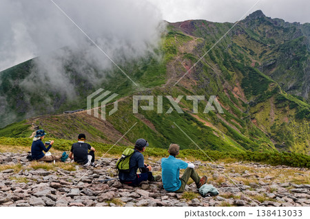 A view of Yokodake and a climber at the summit of Ioudake in the Yatsugatake mountain range. A view of Yokodake and a climber at the summit of Ioudake in the Yatsugatake mountain range. 138413033