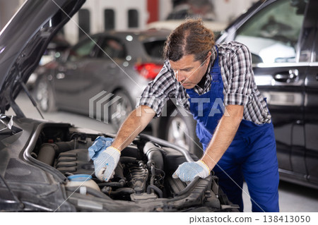 Mechanic man in uniform repairing car in auto repair shop garage 138413050