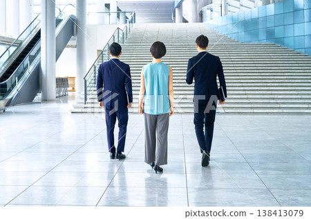 The backs of a business team walking through an office building towards the future. The backs of a business team walking through an office building towards the future. 138413079