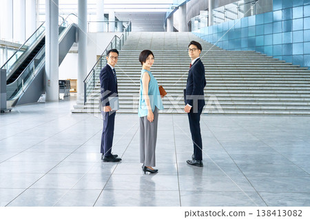 A smiling business team turns around in the lobby of a modern office building. 138413082