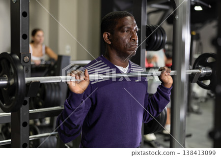 African american man doing barbell squats in gym African american man doing barbell squats in gym 138413099