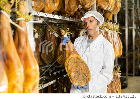Man employee checks jamon. Quality control 138413125