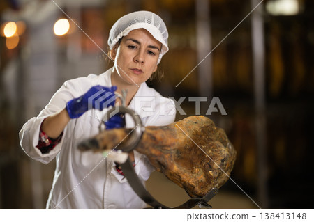 Female worker places ham on a jamonero to cut it into appetizing pieces 138413148