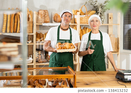 European man and senior woman sellers stands in trading hall of bakery European man and senior woman sellers stands in trading hall of bakery 138413232