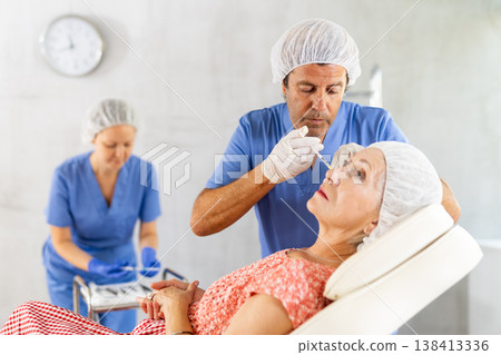 Woman applying rejuvenating treatments by male doctor. 138413336