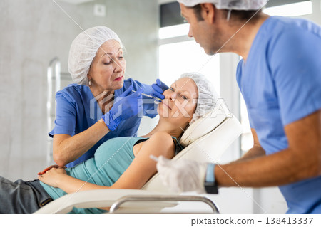 Woman applying rejuvenating treatments by female doctor. 138413337