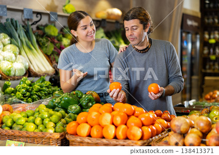 Man and woman choose tangerines and cauliflower in shop Man and woman choose tangerines and cauliflower in shop 138413371