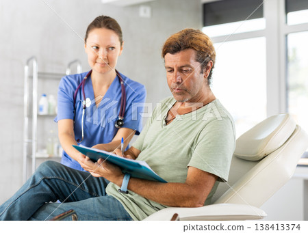 Adult female doctor signing contract with male patient 138413374