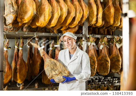 female worker checks the quality of jamon in a factory 138413393