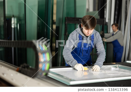 In workshop for production of glass products, guy co-worker cuts off excess from workpiece In workshop for production of glass products, guy co-worker cuts off excess from workpiece 138413396