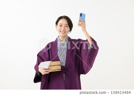 A woman in a yukata holding a smartphone A woman in a yukata holding a smartphone 138413484
