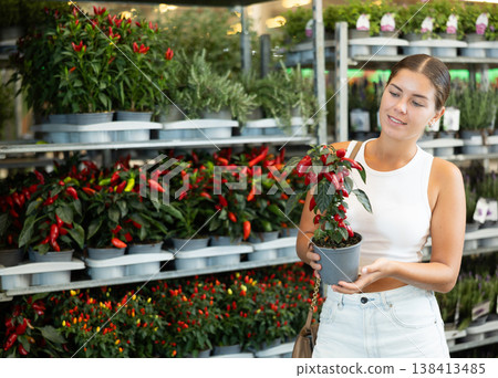 Young girl holding pepper in flower-pot in plants market 138413485