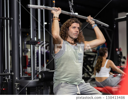 Caucasian man is engaged in a simulator for development of back muscles 138413486