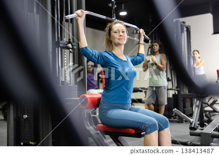 Woman is engaged in a simulator for development of back muscles Woman is engaged in a simulator for development of back muscles 138413487