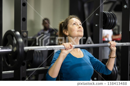 Sportswoman doing exercises with a barbell in gym Sportswoman doing exercises with a barbell in gym 138413488